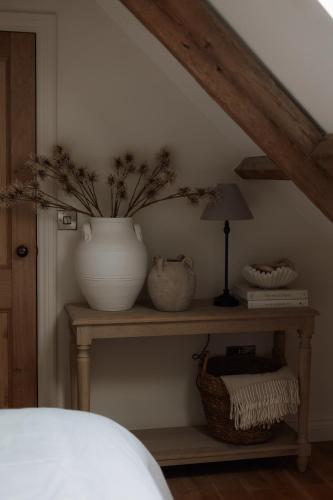 a table with a vase and a lamp on it at Rosa's Loft in Flamborough
