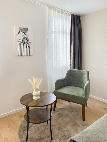 a living room with a green chair and a table at STADT-Hotel Lörrach GbR in Lörrach