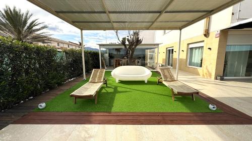 a patio with two benches and a large white table at Casa Del Mar, piscina privada frente al mar in Cullera