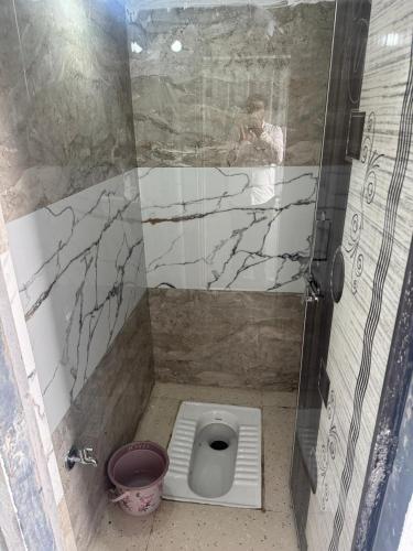 a man taking a picture of a toilet in a shower at Sumai Bhakt Niwas in Tuljapur