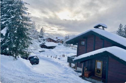 a log cabin with a car parked in the snow at Le Chalet de Nabor in Les Gets