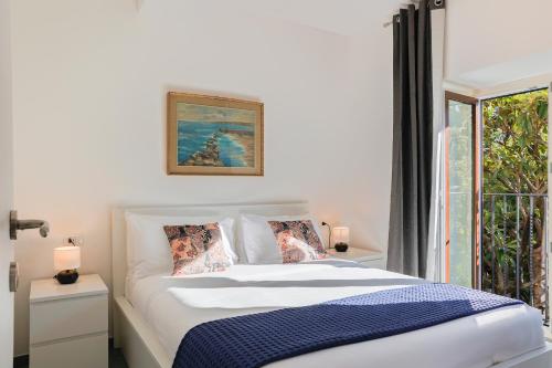 a white bedroom with a bed and a window at Villa Eugenia - Suite Iris in Carate Urio