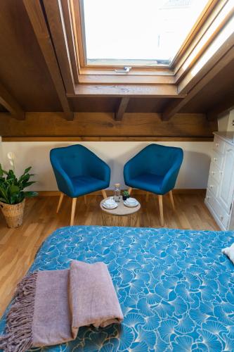 a bedroom with a bed and two blue chairs at Hostal Pension Artilleiro in Santiago de Compostela