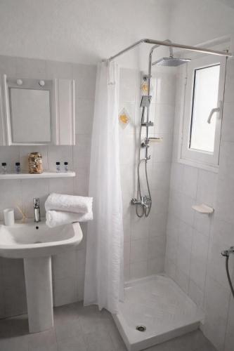 a white bathroom with a shower and a sink at Homeric Poems in Argostoli