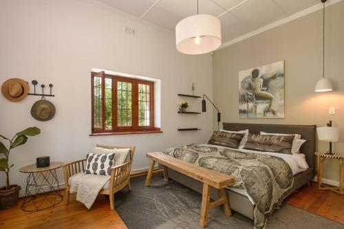 a bedroom with a bed and a bench and a window at Am Flus- at the river in Stellenbosch