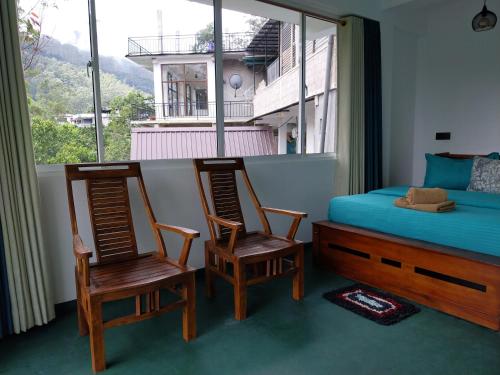 a bedroom with two chairs and a bed and a window at Isha Unity Cottage in Nallathanniya