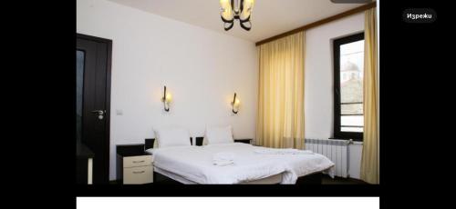 a bedroom with a white bed and a window at Златоград in Zlatograd