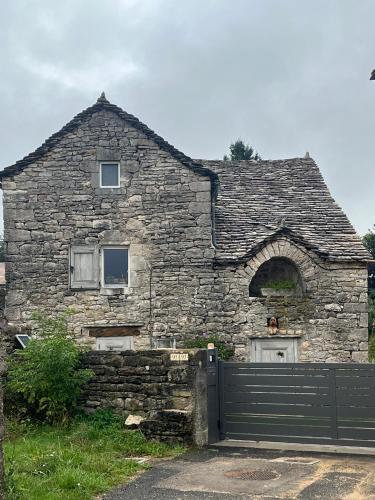 an old stone house with a gate in front of it at Chambre d'hôtes Caussenarde in Le Massegros