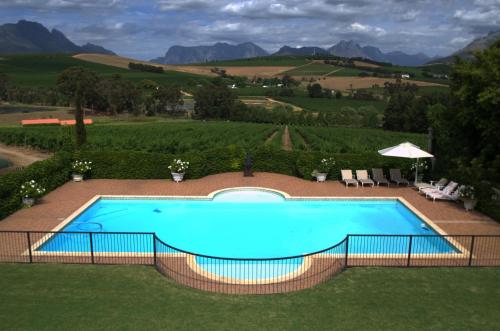 ein Schwimmbad inmitten eines Rasens mit Bergen in der Unterkunft Clos Malverne Wine Estate in Stellenbosch