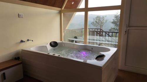 a bath tub in a room with a large window at Idukki Nook in Idukki