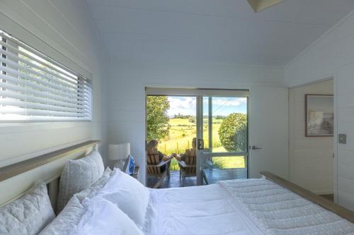 a bedroom with a bed and a woman sitting in a chair at Hideaway Cottage, Tauranga, so close to Bethlehem & Mount Maunganui in Tauranga