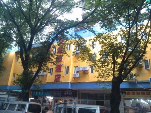 un gran edificio amarillo con coches estacionados frente a él en 7Days Inn Guangzhou Beijing Road Subway Station en Cantón