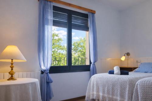 a bedroom with a window with blue curtains and a bed at Apartament amb llar de foc - Golfes Cal Gravat in Montsonis