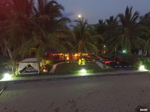 a view of a resort at night with palm trees at Luxury Sakina Villa - Beachfront in Dzamandzar