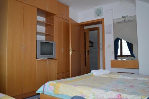 a bedroom with a bed and a tv and cabinets at Guest House Vila Horizont in Goč
