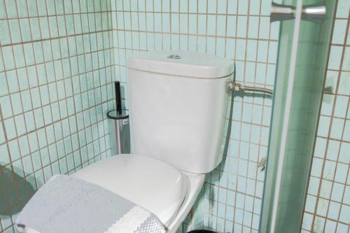 a white toilet in a bathroom with white tiles at Lak Peristeri Homes 50m from metro station in Athens