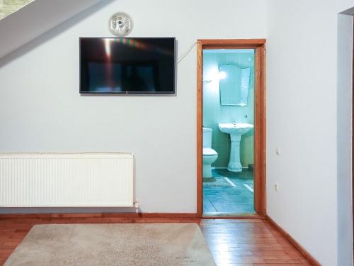 a bathroom with a toilet and a tv on a wall at Casa de vacanță in Călimăneşti