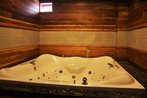 a bath tub in a bathroom with wooden walls at Metro Hotel & Spa in Thung Song