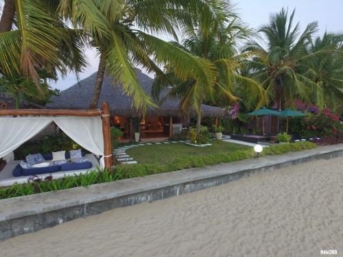 a resort with a tent and palm trees on a beach at Luxury Sakina Villa - Beachfront in Dzamandzar