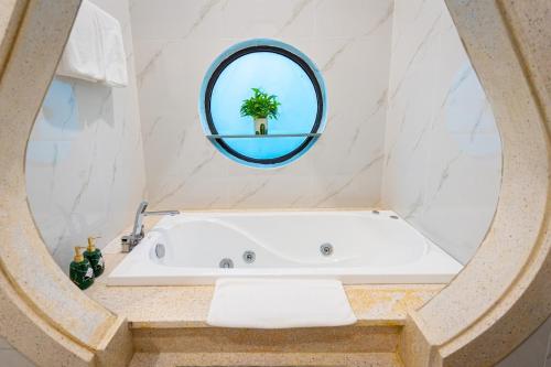 a bath tub in a bathroom with a round mirror at B'Villa Luxury in Dong Hoi