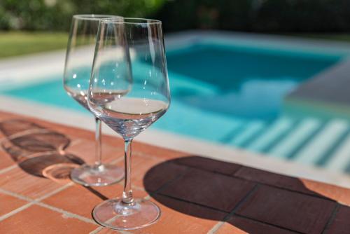 two wine glasses sitting on a table next to a swimming pool at Villa Almond in Taormina