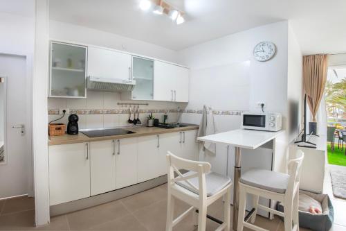 a kitchen with white cabinets and a table and chairs at Relax studio Primavera in Las Galletas