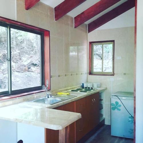 a large kitchen with a sink and a window at Cafeteria y cabañas Eluney - Koigue in Pucón