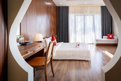 a bedroom with a bed and a desk and a chair at B'Villa Luxury in Dong Hoi