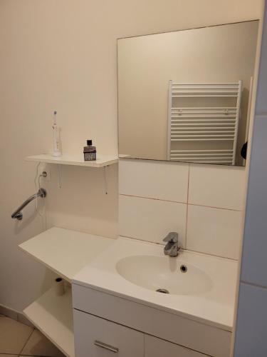 a white bathroom with a sink and a mirror at Lieu charmant in Gimeux