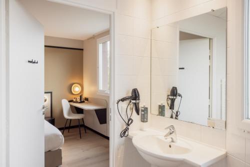 a bathroom with a sink and a phone on the wall at Brit Hotel Saint-Méen-le-Grand en Brocéliande in Saint-Onen-la-Chapelle