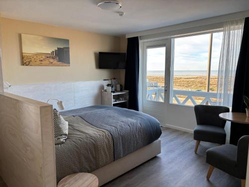 a bedroom with a bed and a balcony with a view at Bed&Breakfast aan Strand in Katwijk aan Zee