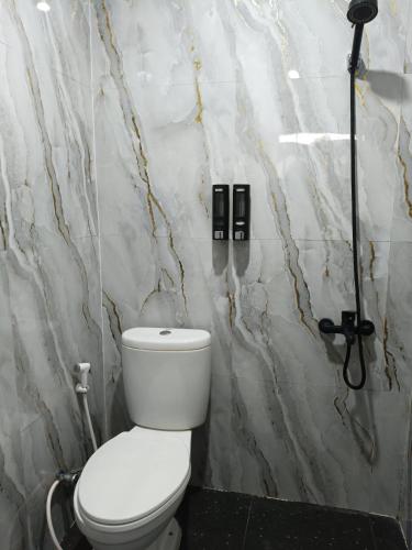 a bathroom with a toilet and a marble wall at MEWAH guest house in Karangploso