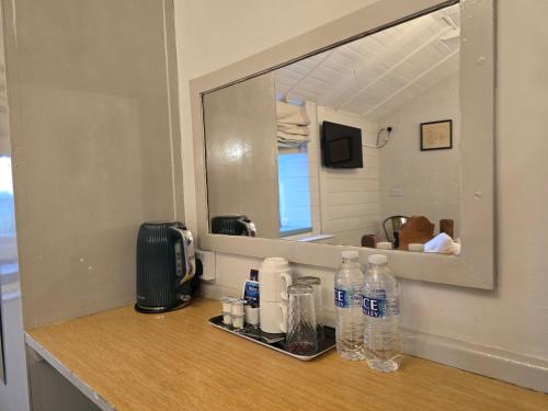 a bathroom counter with bottles of water and a mirror at Littledean House Hotel in Cinderford