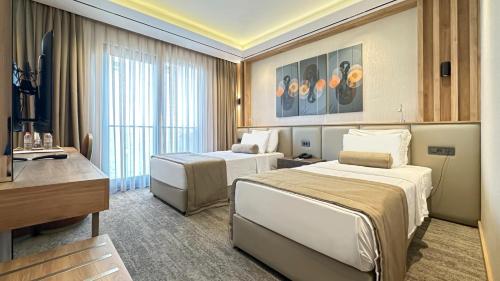 a hotel room with two beds and a desk at Solia Hotel in Mezitli