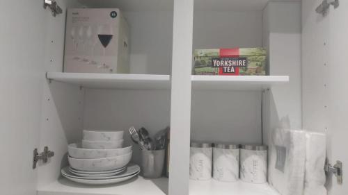 a white cabinet with plates and utensils in it at Serene and Cosy Private Studio in Milton Keynes