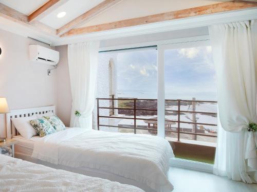 a bedroom with a bed and a large window at Pension Haneul Tari in Jeju