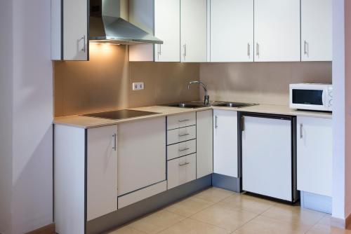 a kitchen with white cabinets and a sink and a microwave at Apartments Sorrabona in Pineda de Mar