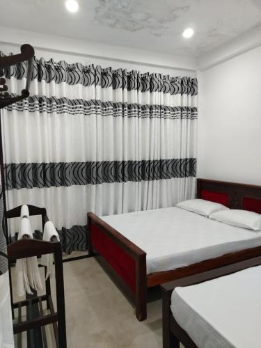 a bedroom with two beds and a curtain at Hotel Diamond Palace in Bibile
