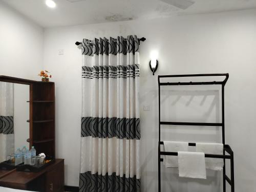 a bathroom with a shower curtain and a mirror at Hotel Diamond Palace in Bibile