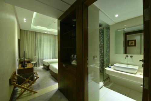 a bathroom with a tub and a sink and a bed at Al Masa Hotel Nasr City in Cairo