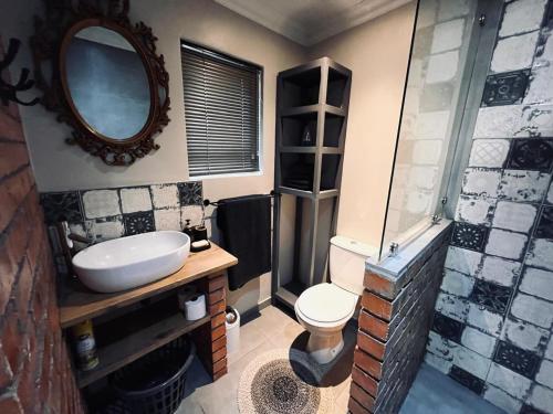 a bathroom with a sink and a toilet and a mirror at Otista Self-Catering Cottage Bloemfontein in Bloemfontein