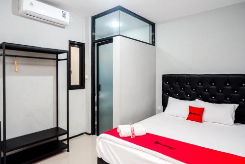 a bedroom with a bed with a red blanket at RedDoorz Plus @ Kalpataru in Rampal