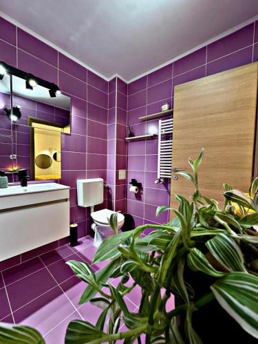 a purple bathroom with a toilet and a plant at VerdeViu Apartments 2 Prima Green Residence in Oradea