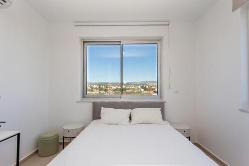 a white bedroom with a large white bed and a window at BlueBell Limassol Suites in Limassol