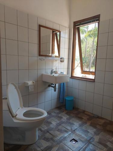 a bathroom with a toilet and a sink and a window at Arche Noah in Kalabahi