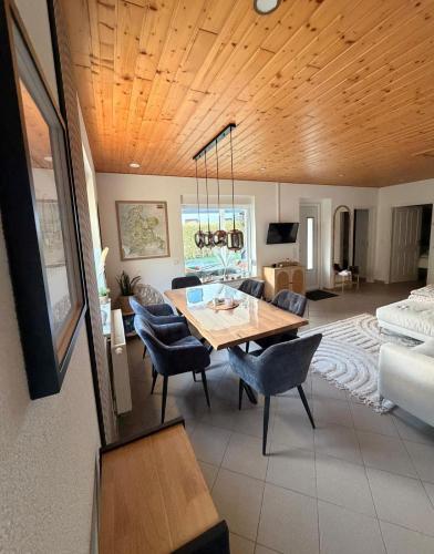 a living room with a wooden ceiling and a table and chairs at ZweiundMeer Bungalow 1 in Wiek auf Rügen