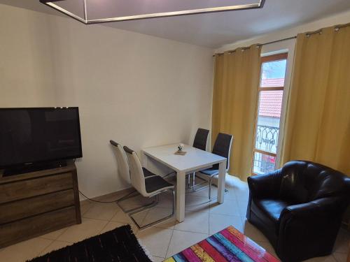 a living room with a table and chairs and a television at Monelly Apartman in Komárno