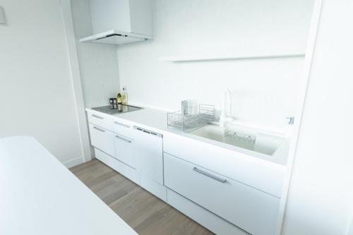 a white kitchen with white cabinets and a sink at villa costa del sol ヴィラ コスタ デル ソル 淡路島 in Awaji