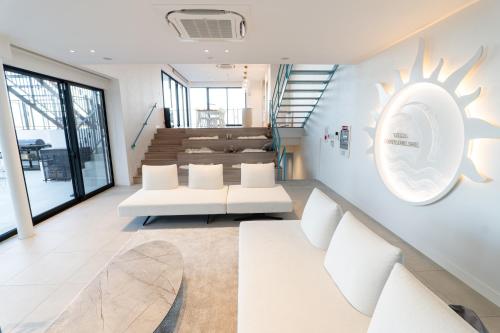a living room with white furniture and a staircase at villa costa del sol ヴィラ コスタ デル ソル 淡路島 in Awaji