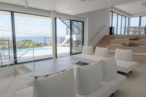 a living room with white furniture and large windows at villa costa del sol ヴィラ コスタ デル ソル 淡路島 in Awaji